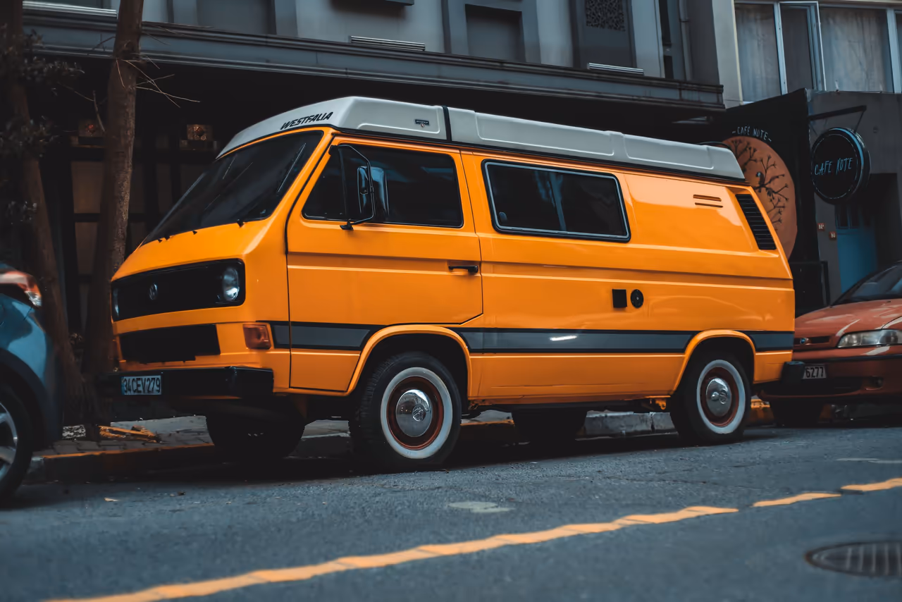 An orange camper van parked on a city street