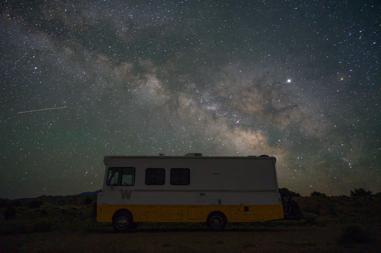 An old RV parked in the desert under the Milky Way